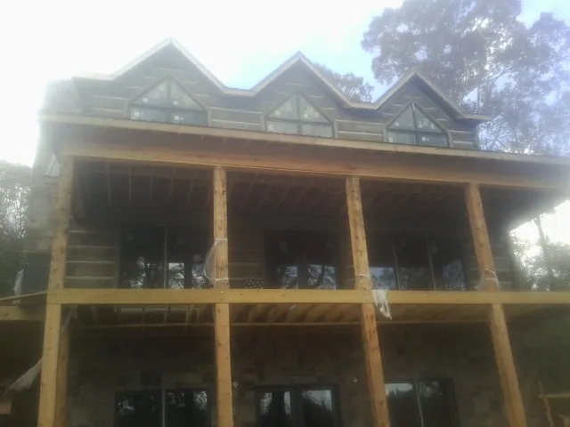 Dormers and porch framing on a large log home under construction — Roof Coating work by our crew in Rainbow City