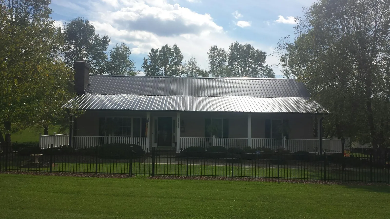 Gray metal roof on a brick ranch with a full width front porch — Gutter Guard Installation work by our crew in Rainbow City
