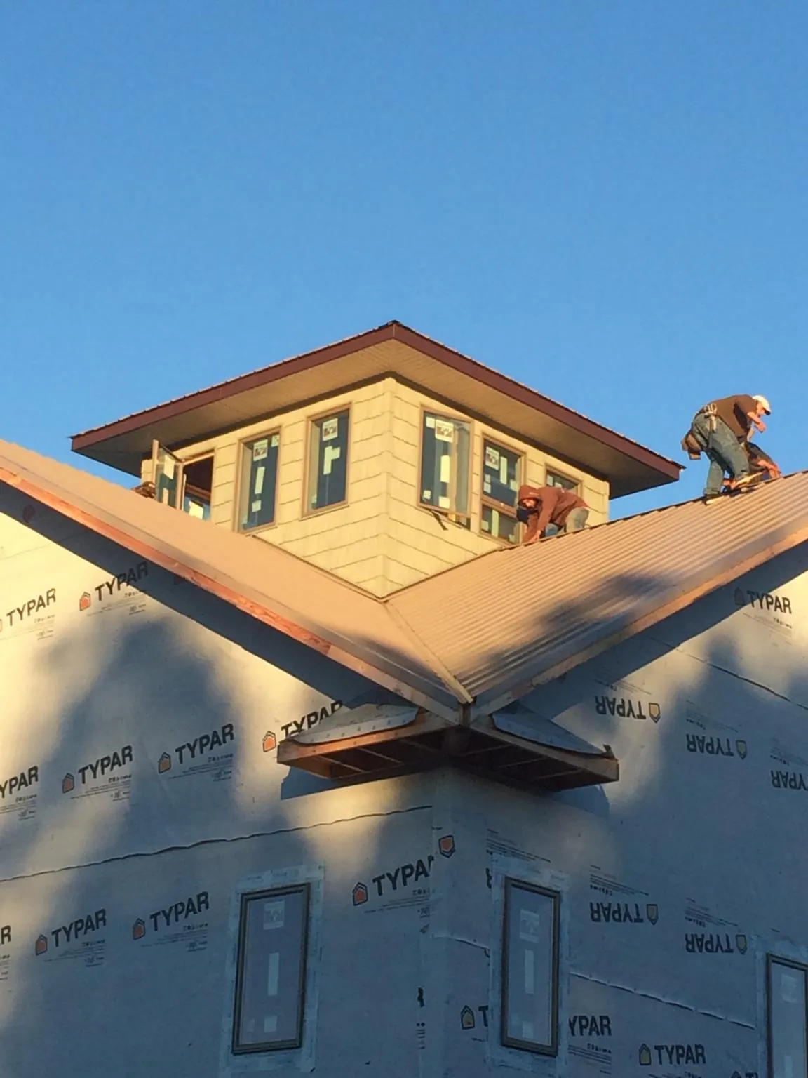 Roofers working around a rooftop cupola on a new metal roof at sunset — Roof Waterproofing in Rainbow City by Roofing Brothers